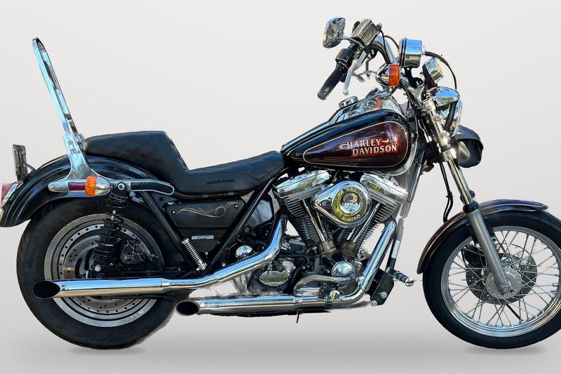 A black and burgundy FXR with a chrome sissy bar and laced front wheel, on a plain grey backdrop. Not the bike for sale.